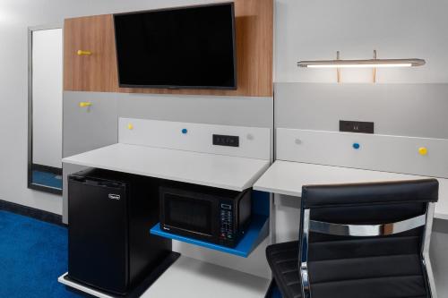 a kitchen with a desk with a microwave and a tv at Microtel Inn by Wyndham Janesville in Janesville