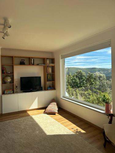 a living room with a large window and a television at Casa do Beco in Moninho
