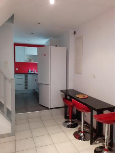 La cuisine est équipée d'une table noire, de chaises rouges et d'un réfrigérateur. dans l'établissement T3 duplex calme à la Timone, à Marseille