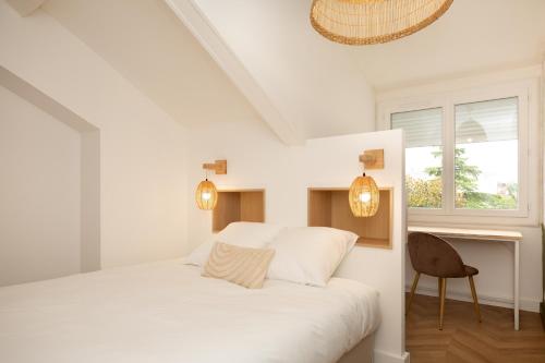 une chambre blanche avec un lit et une chaise dans l'établissement Le Refuge - Au coeur de Dax, à Dax