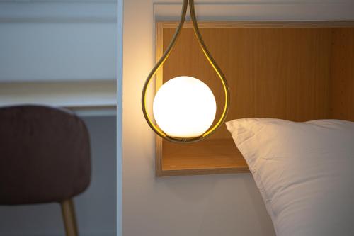 - une lumière sur le côté du lit avec un oreiller dans l'établissement Le Zénith - Central à Dax, à Dax