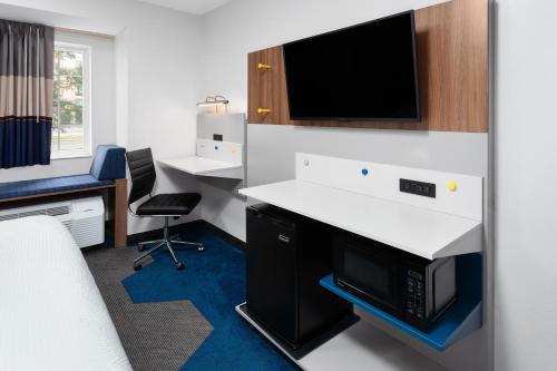 an office with a desk and a tv on a wall at Microtel Inn by Wyndham Janesville in Janesville