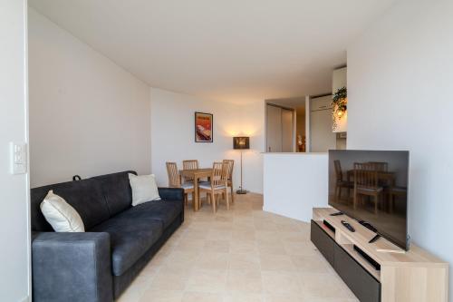 un salon avec un canapé et une télévision dans l'établissement Atlantic Selection - Vue Océan - La Sud Hossegor, à Soorts-Hossegor