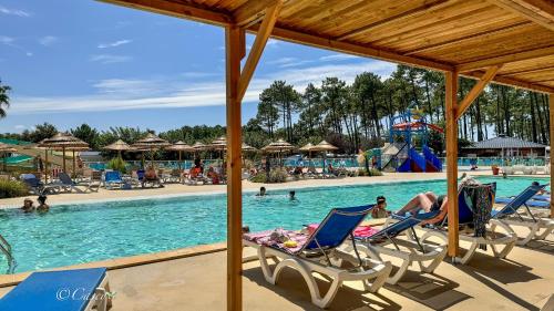 - une piscine avec des chaises et des personnes dans l'eau dans l'établissement Bungalow 2 Chambres Avec Clim, à Saint-Julien-en-Born