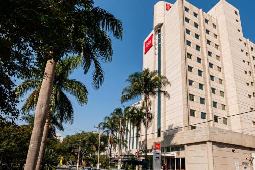 a tall white building with palm trees in front of it at ibis Santo Andre in Santo André