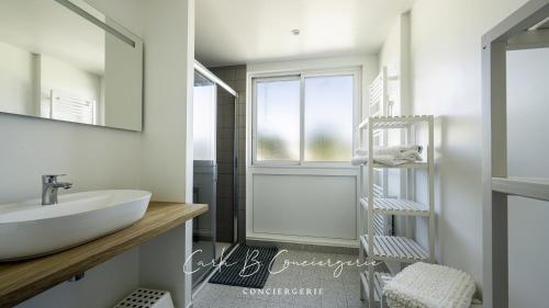une salle de bain avec un lavabo et un miroir dans l'établissement LE BELVEDERE - Appartement pleine vue mer 6 pers Concarneau, à Concarneau