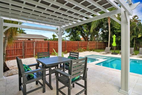 a table and chairs under a white pergola next to a pool at Little Beach House w/ POOL&SPA - 5 minutes to Vanderbilt Beach (Pet Friendly) in Naples