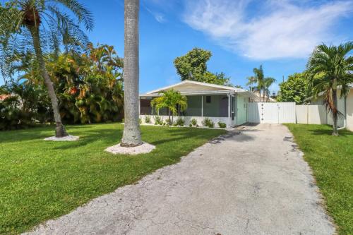 a house with a palm tree and a driveway at Little Beach House w/ POOL&SPA - 5 minutes to Vanderbilt Beach (Pet Friendly) in Naples