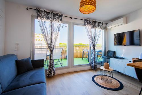 Una sala de estar con un sofá y una ventana grande. en T2 - Terrasse - 3 min à pieds des plages- Parking privée - Clim - Wifi - 4 PAX, en La Grande-Motte