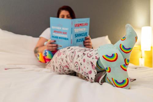 a woman laying on a bed reading a book at ibis Santo Andre in Santo André