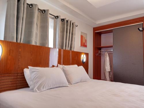 a bedroom with a white bed with a wooden headboard at Masayi Residences in Adentan