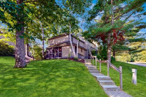 a house on a lawn with a fence and trees at Samoset Vacation in Gilford