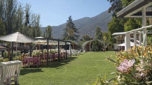 a garden with tables and chairs and umbrellas at Hotel La Calma De Rita - Pirque in Pirque