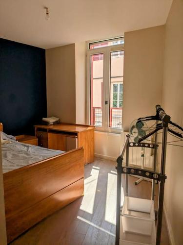 une chambre avec un lit, un bureau et une fenêtre dans l'établissement Bel appartement en rue piétonne, à Roanne