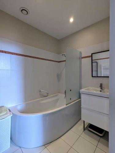 une salle de bain blanche avec une baignoire et un lavabo dans l'établissement Bel appartement en rue piétonne, à Roanne