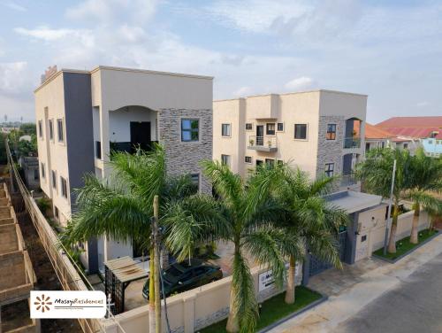 a building with palm trees in front of it at Masayi Residences in Adentan
