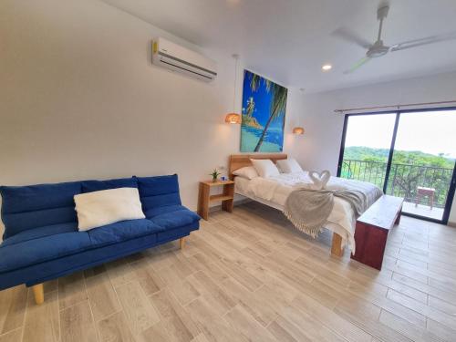 a living room with a blue couch and a bed at Pinilla Highlands Incredible mountain views in Tamarindo