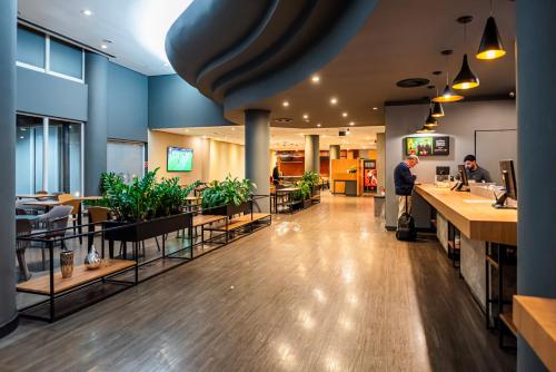 a lobby of a restaurant with tables and plants at ibis Santo Andre in Santo André