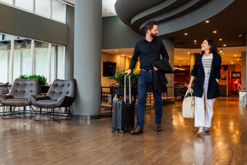 a man and woman walking through a lobby with their luggage at ibis Santo Andre in Santo André