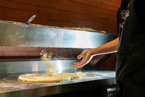 a person is making a pizza on a grill at ibis Santo Andre in Santo André