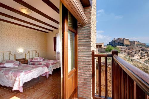 a room with two beds and a balcony at Apartamentos Bellavista in Alquézar