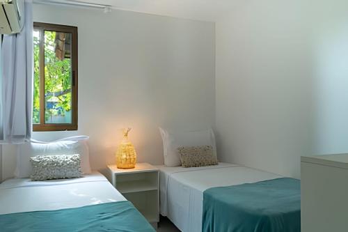 ポルト・デ・ガリーニャスにあるLC Casas de Praia - Chalé 3 centrinho de Portoのベッドが2つと窓がある白い部屋