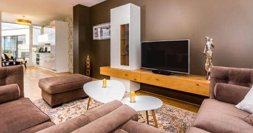 a living room with two couches and a flat screen tv at VotivPark Vienna Serviced Apartments in Vienna