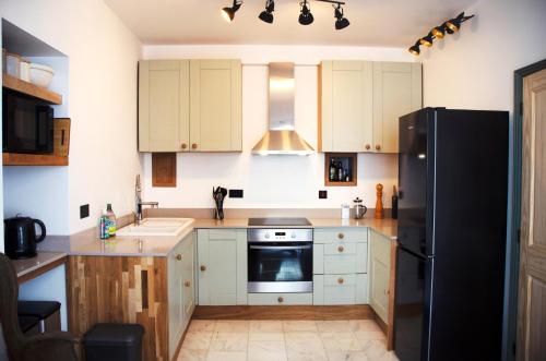 a kitchen with white cabinets and a black refrigerator at Wellington House Boutique Holiday Let in Falmouth