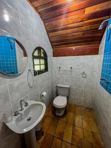 a bathroom with a sink and a toilet and a mirror at Casa de Barro - Chalés in Santo Antônio do Pinhal