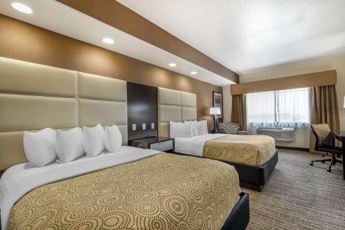 a hotel room with two beds and a desk at Best Western Plus Lackland Hotel and Suites. in San Antonio