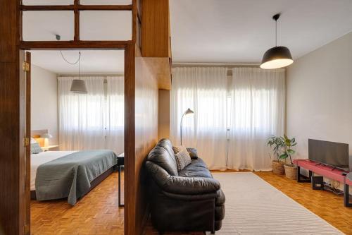 a bedroom with a couch in front of a bed at Julio Dinis Studio in Porto