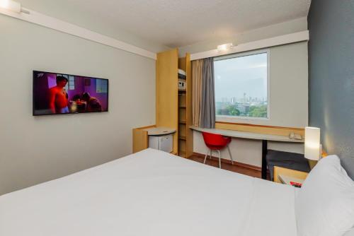 a hotel room with a bed and a desk and a window at ibis Santo Andre in Santo André
