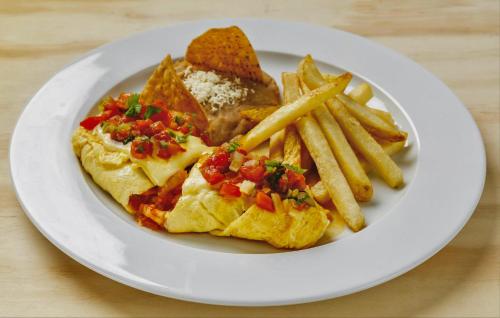 a plate of food with a omelet and french fries at Hotel Maioris Kumate Culiacán in Culiacán