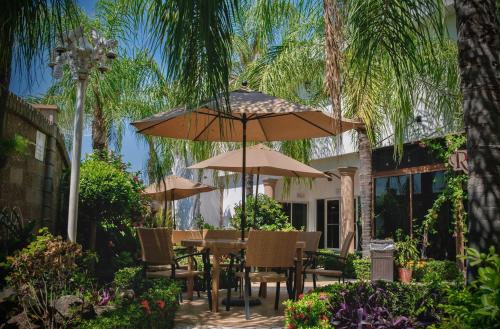 a table and chairs with umbrellas in a garden at Hotel Maioris Kumate Culiacán in Culiacán