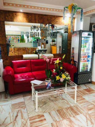a living room with a red couch and flowers on a table at Hotel Presidente Vicente Guerrero in Chilpancingo de los Bravos