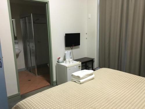 a bedroom with a bed and a television and a bathroom at Amaroo Hotel Dubbo in Dubbo