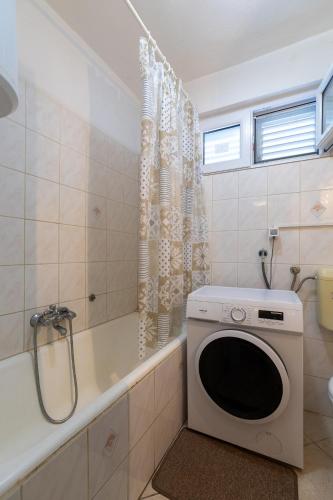 a bathroom with a tub and a washing machine at Apartments by the sea Cove Zarace - Gdinj, Hvar - 2047 in Gdinj