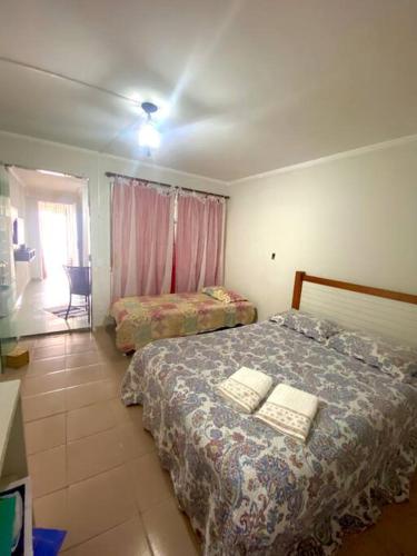 a bedroom with two beds and a table and a window at Porto Allegra in Cabo Frio