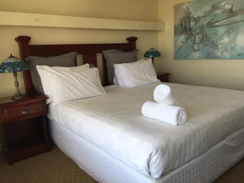 a bedroom with a bed with two folded towels on it at Aberdeen Motor Inn in Geelong