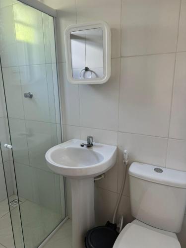 a bathroom with a sink and a toilet and a mirror at Pousada Horizonte in Ilha de Boipeba