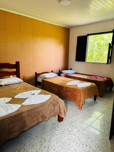 a hotel room with two beds and a window at Pousada Horizonte in Ilha de Boipeba