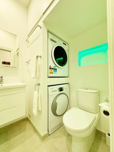 a bathroom with a toilet and a washing machine at Park views, fast wifi, washer & dryer in Auckland
