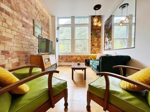 a living room with green furniture and a brick wall at Park views, fast wifi, washer & dryer in Auckland