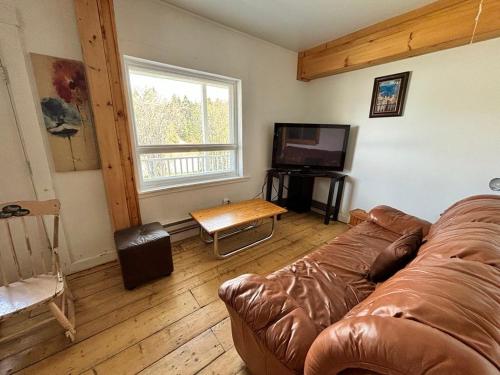 a living room with a couch and a television at Résidences touristiques l’Abris in LʼAnse-Saint-Jean