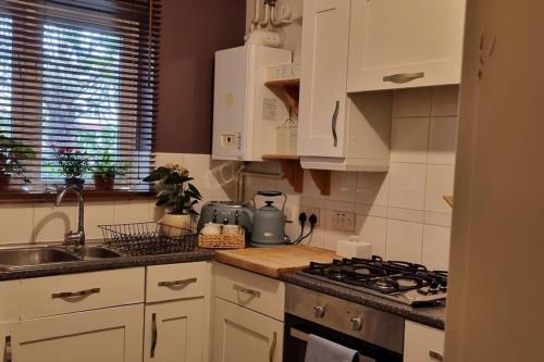 a kitchen with white cabinets and a stove top oven at Spacious Studio with Free Parking West Molesey KT8 in West Molesey