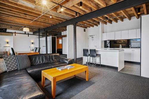 a living room with a black leather couch and a table at Gibson Mill waterfront warehouse apartment - 101 in Hobart