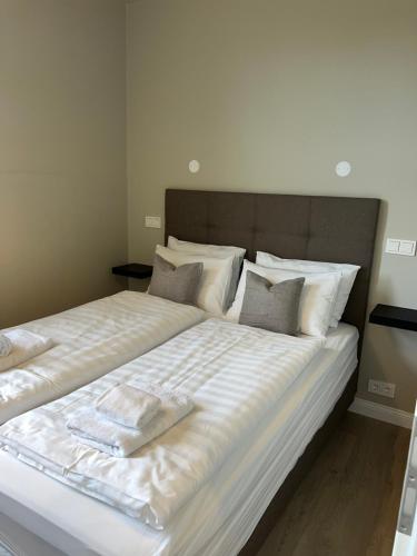a large white bed with white sheets and pillows at Erobik Apartments in Höfn