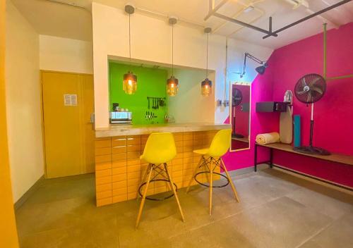 a kitchen with yellow and pink walls and two yellow stools at Hotel Estancias VIVE MX wtc CDMX, Trademark by Wyndham in Mexico City