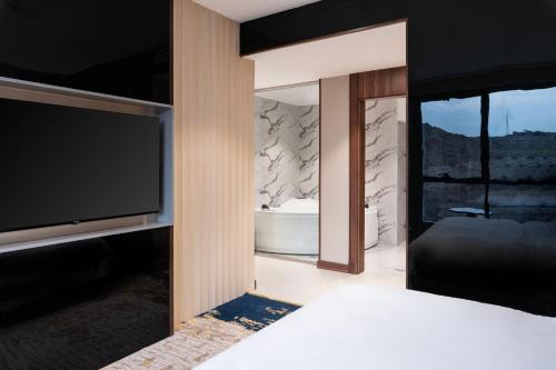 a bedroom with a tv and a bed and a tub at Warwick Al Taif Hotel in Taif