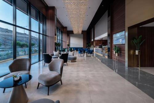 a lobby with chairs and tables and windows at Warwick Al Taif Hotel in Taif